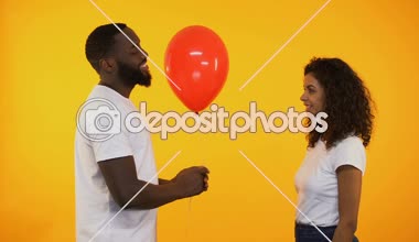 Gülümseyen Afro-Amerikan adam balon sunan sevimli kadın, doğum günü hediyesi, Tarih