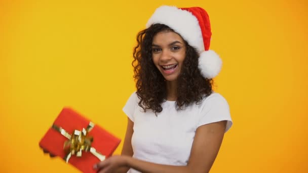 Fröhliche Mischlingsfrau Mit Weihnachtsmann Hut Roter Geschenkbox Und Lächelnd — Stockvideo