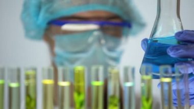 Kimyager tüp yeşil bitki ve mavi sıvıyı şişeye, bilim ile karşılaştırma