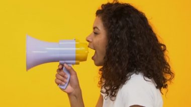 Genç ve güzel kadın megafon sarı arka plan, reklam üzerine bağırarak