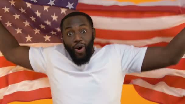 スポーツ感動の全国代表チームを支えるアメリカの国旗と黒の若い男 — ストック動画