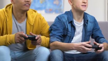 İki genç çocuklar dostluk kanepede oturan rekabetçi video oyun oynarken
