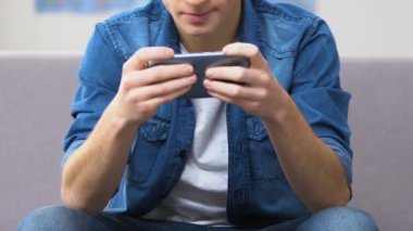 Smartphone, hızlı tempolu video oyun oynarken kendinden geçmiş genç boş zaman