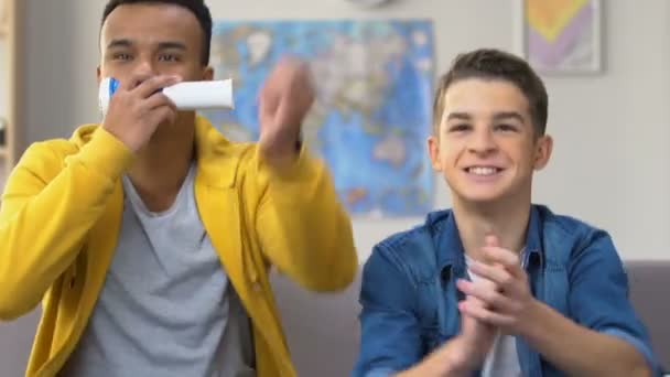 Zwei Männliche Teenager Sehen Fußballspiel Fernsehen Singen Und Blasen — Stockvideo