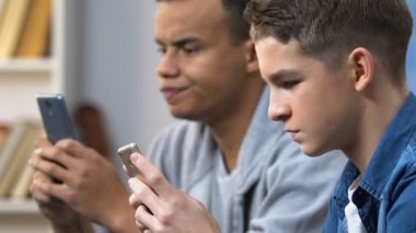 Akıllı telefonlar üzerinde mobil oyunlar oynayan iki lise arkadaşı rahat hafta sonu