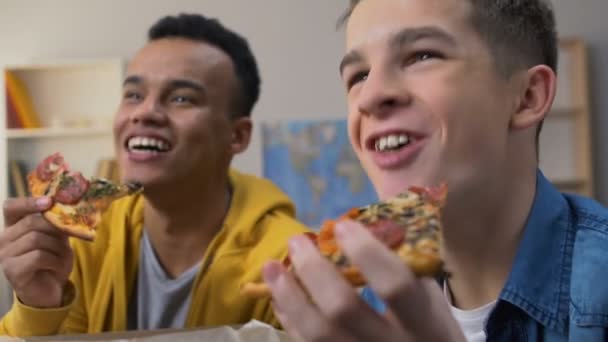两个朋友一边吃披萨一边笑着 在电视上看情景喜剧系列 — 图库视频影像