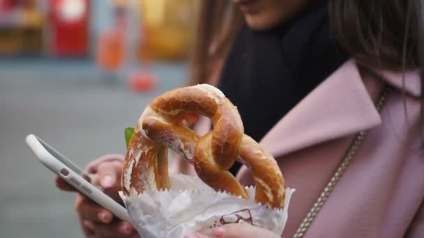 Donna d'affari che fa merenda con pretzel mentre lavora sul cellulare all'aperto — Video Stock