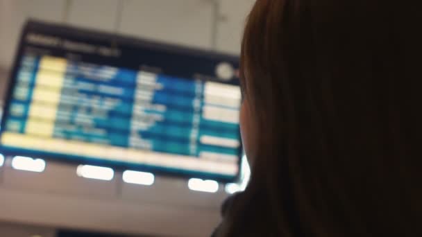 Mujer mirando el tablero de exhibición del aeropuerto, comprobando el estado de vuelo de salida de cerca — Vídeo de stock