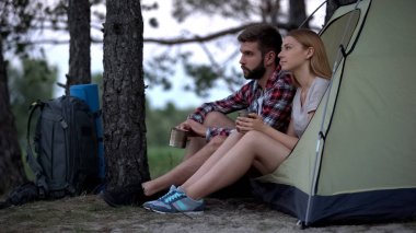 Çadırda oturan ve doğada dinlenme demir bardak içme turist birkaç
