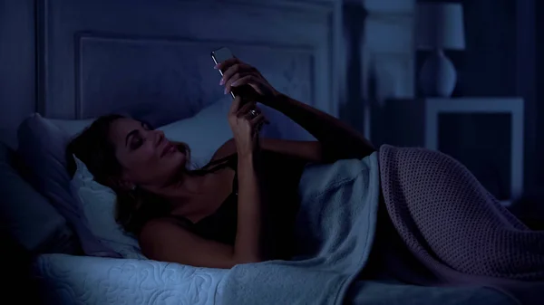 美丽的女人有视频通话与丈夫 躺在床上 商务旅行 — 图库照片