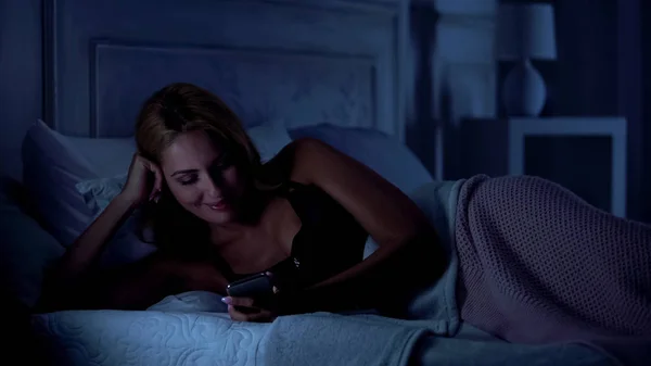 微笑的女士在网上观看有趣的视频 睡觉前玩得开心 — 图库照片