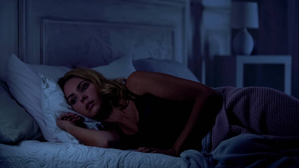 Беспокойная женщина не может спать по ночам, думая о жизненных трудностях, стрессе
