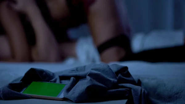 智能手机躺在床上 情侣在背景上做爱 绿色屏幕 — 图库照片