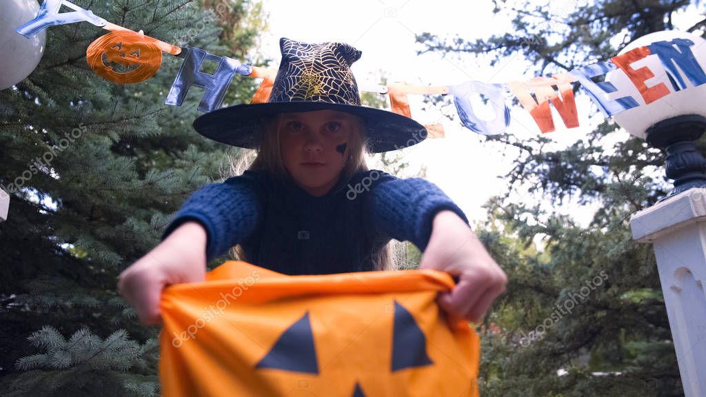 Girl holding Trick or Treat bag, demanding sweets at party entrance, Halloween