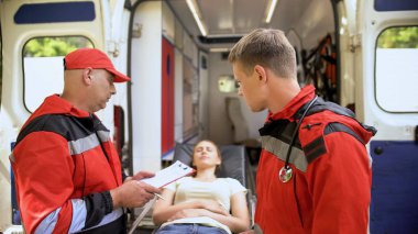 Erkek ambulans sedye üzerinde hasta kayıtları, yapım inceleyerek kurtarma ekibi