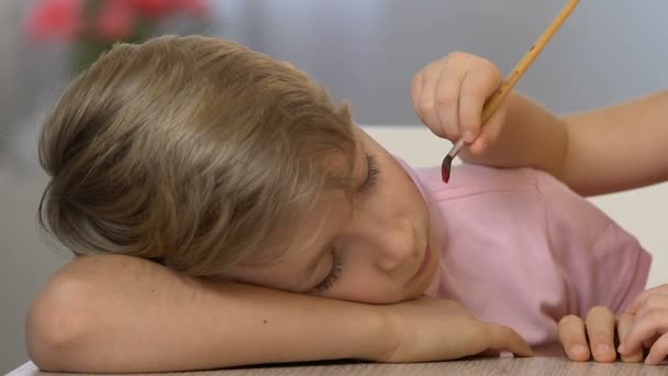 Petite soeur peignant sur le visage du garçon endormi, enfance heureuse, blague drôle — Video