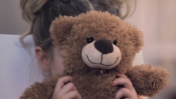 Αναστατωμένος κορίτσι κρύβεται πίσω από την teddy και δυστυχώς βλέπουν κάμερα, πρόγραμμα υιοθεσίας — Αρχείο Βίντεο