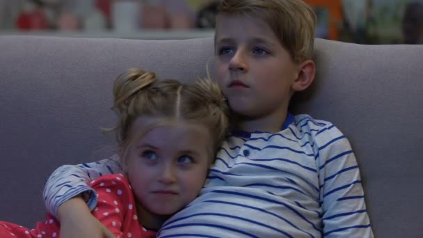 Cansado hermano y hermana viendo la televisión por la noche, chico protege a chica asustada, horror — Vídeo de stock