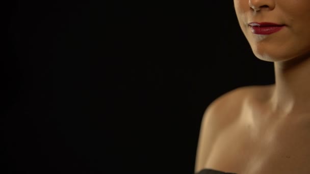 Улыбающаяся женщина показывает чип азартных игр в камеру, изолированный на черном фоне — стоковое видео