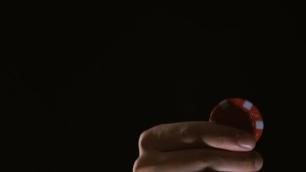 Человек вращается чип в руке на черном фоне, знак судьбы, казино — стоковое видео