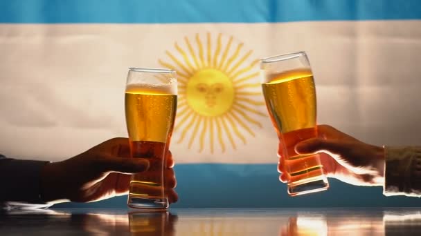 Dua pria mengklik gelas bir dengan latar belakang bendera Argentina, slow-mo — Stok Video