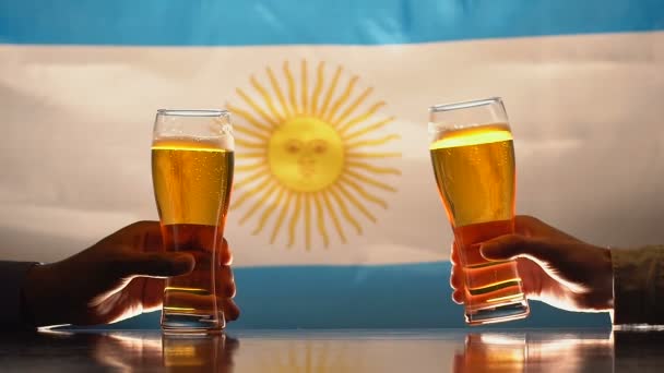 Mannen rammelende bierglazen, Argentijnse vlag op de achtergrond, nationale feestdag — Stockvideo