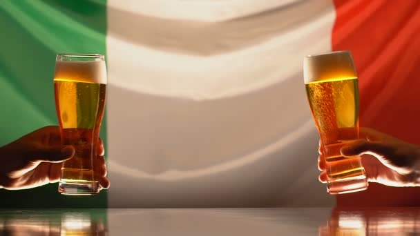 Hombres tintineando vasos de cerveza, bandera italiana en el fondo, celebración del festival — Vídeo de stock