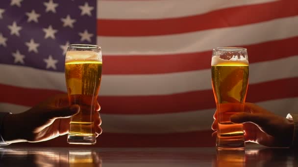 Two men clinking beer glasses against USA flag, independence day celebration — Stock Video