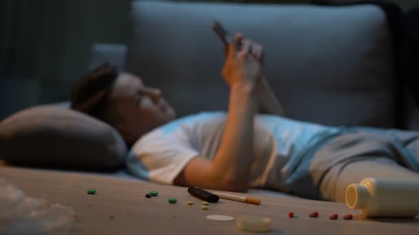 Kaydırma telefon, ilaç kapsül ve tablo üzerinde sigara bağımlısı genç — Stok video