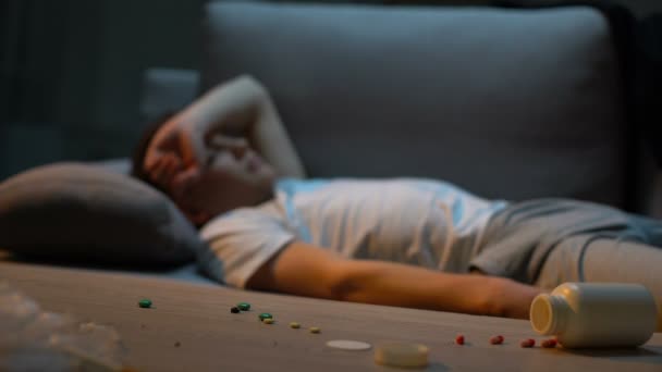 Депресивний підліток лежить на дивані, передозування ліками, знеболююча купа на столі — стокове відео