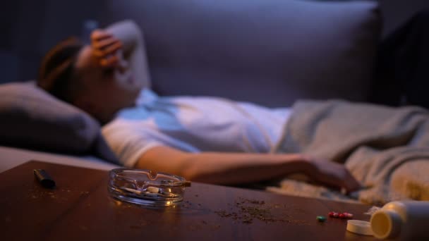 Teenager sleeping on sofa after smoking and taking drugs idle life harmful habit — Stock Video