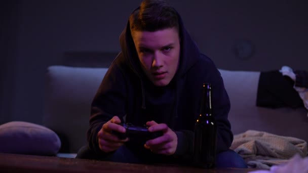 Родители ловят сына-подростка, пьющего пиво и играющего в видеоигры, бунтарского возраста — стоковое видео