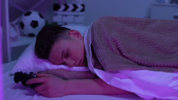 Сплячий підліток тримає джойстик, ігрову залежність, психічну та медичну шкоду — стокове відео
