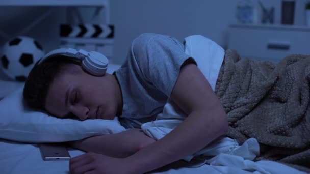 Male teenage boy fallen asleep in headphones, overworked student relaxing — Stock Video