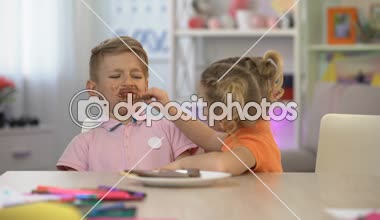 Mutlu kardeş kardeşi besleme ile çikolata, şeker çürük overeating, bulaşmış.