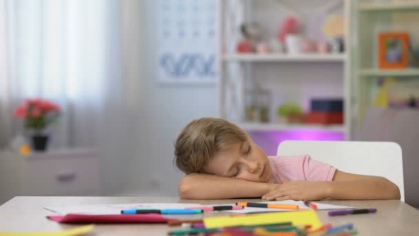 Niño en edad preescolar durmiendo en el escritorio, lápices de color y papel en la mesa del jardín de infantes — Vídeos de Stock