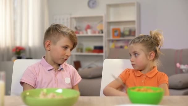 Colegial cosquillas hermana pequeña, jugando durante el desayuno, comunicación familiar — Vídeo de stock