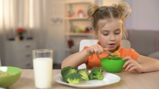 Niedliche Tochter isst Frühstückscerealien mit Milch, Mutter streichelt Mädchen den Kopf — Stockvideo