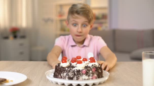 Chico feliz comiendo cereza de la parte superior de pastel de crema, postre dulce, snack de la infancia — Vídeos de Stock