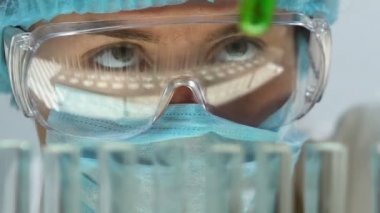 Yeşil sıvı test tüpü içinde ekleme laboratuar asistanı kimyasal reaksiyon izleme