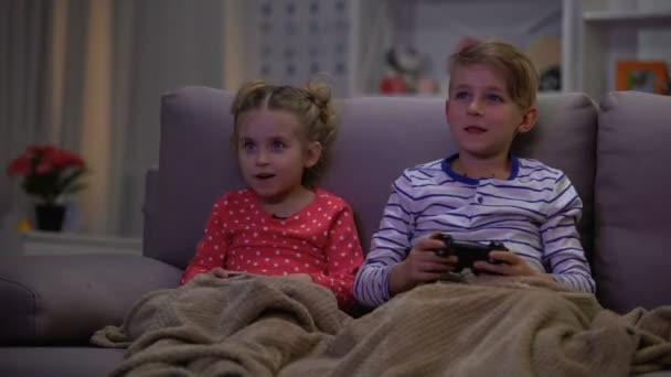 Irmão brincando com irmã cobrindo com cobertor, crianças jogando noite jogo online — Vídeo de Stock