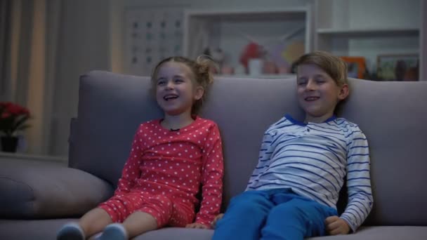 Broer en zus kijken naar grappige cartoon samen's avondentertainment glimlachen — Stockvideo