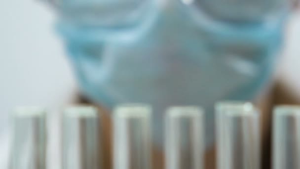 Laboratory assistant doing chemical analysis, test tubes reflecting in glasses — Stock Video