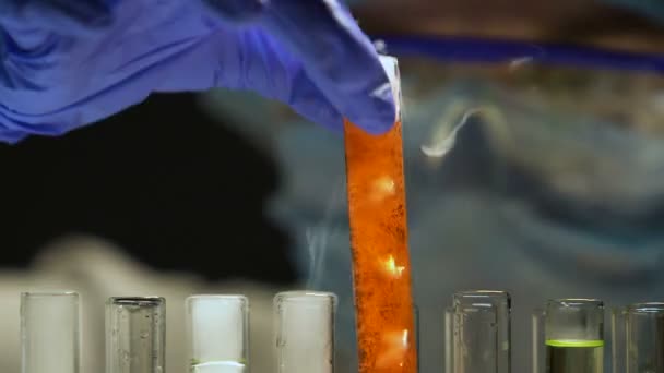 Chemist taking test tube with boiling liquid, looking at sediments on bottom — Stock Video