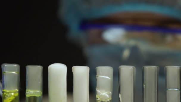 Исследователь берет пробирку с голубой кипящей жидкостью, анализирует отложения — стоковое видео