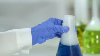 Laboratuar işçisi şişesi kaynar sıvı, Farmakoloji mavi ile karıştırarak eldiven