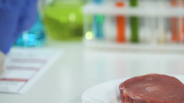 Scientist holding tablet on background of piece of meat, artificial products — Stock Video