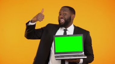 Neşeli Afro-Amerikan işadamı prekeyed laptop ve başparmak-up jest gösterilen