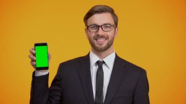Yeşil ekranlı akıllı telefon tutarak takım elbiseli adam iş app Yaşasın gösterilen