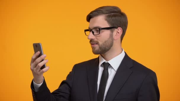 Hombre desplazándose teléfono inteligente y sonriendo a la cámara, aplicación útil de negocios — Vídeo de stock